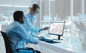 Two scientists in the lab reviewing bioprocessing data visualizations on a computer monitor