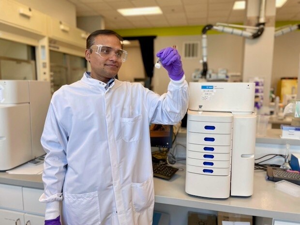 Karwa no laborat&oacute;rio ao lado de um instrumento anal&iacute;tico que ajuda a determinar a pureza do mRNA.